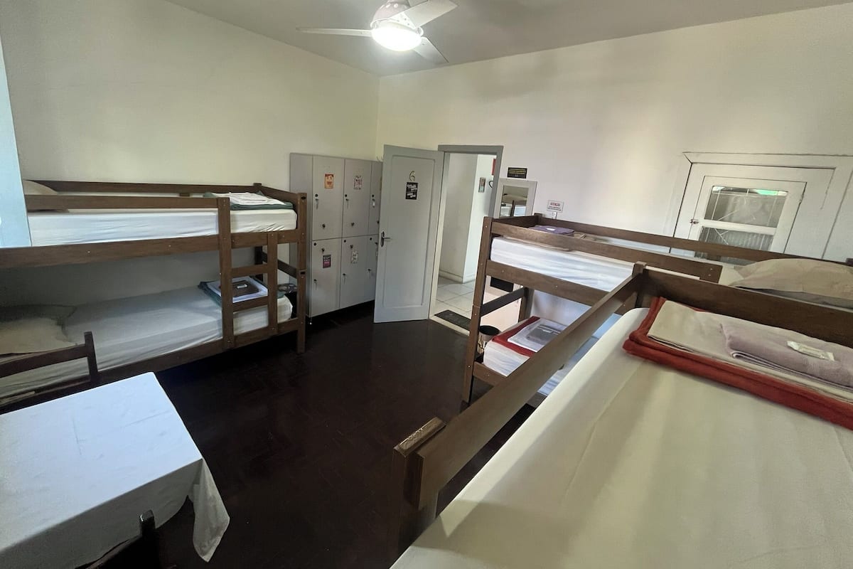 A dormitory room with bunk beds, a ceiling fan, and a door with a window.