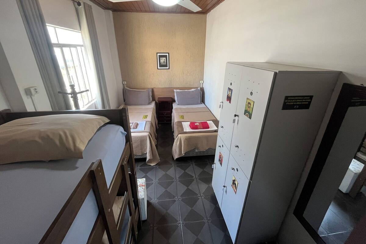 A compact hotel room with a single bed, two bedside tables, a small desk, and a refrigerator.