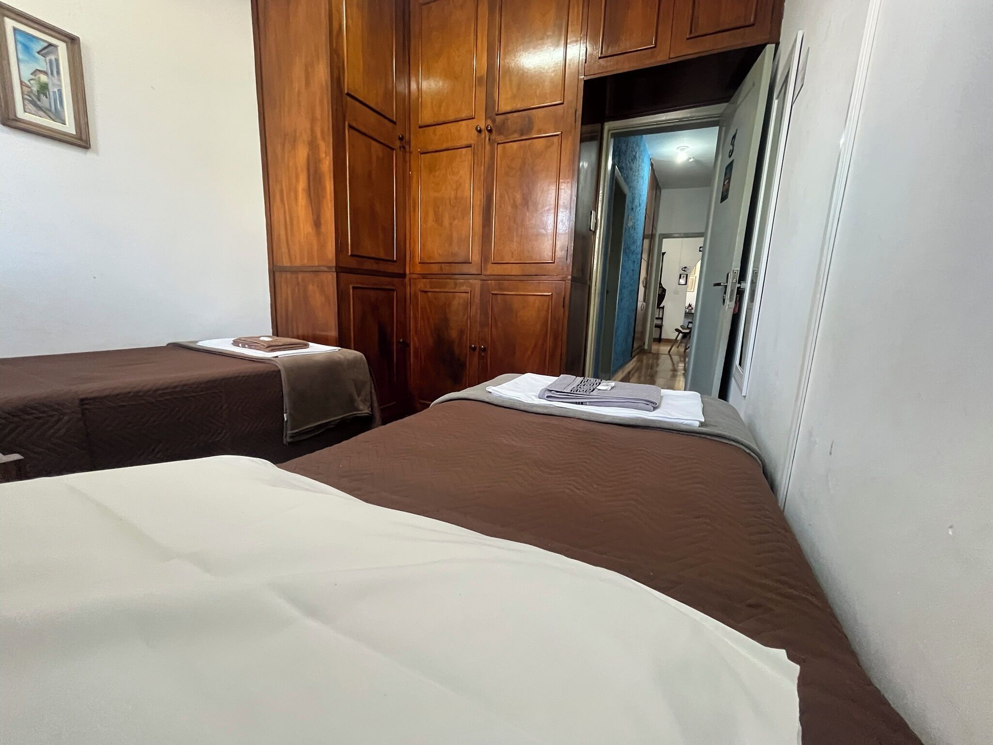 Un dormitorio con dos camas, armarios de madera y una puerta que da a otra habitación.