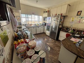 A kitchen with a refrigerator, microwave, and various food items on the counter. - Rota BH Hostel (Belo Horizonte)