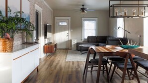 Une cuisine moderne avec des meubles blancs, une table à manger en bois et un ventilateur de plafond.