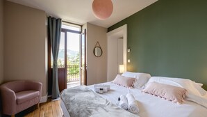 A hotel room with a bed, a chair, a balcony with a view, and a round mirror on the wall. - Le Paradis - Beautiful T3 with nice view on the Visitation (Annecy)