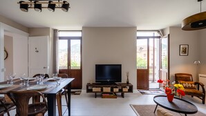 A spacious living area with a dining table set for six, a flat-screen TV, and a comfortable seating area with a sofa and armchair. - Le Paradis - Beautiful T3 with nice view on the Visitation (Annecy)