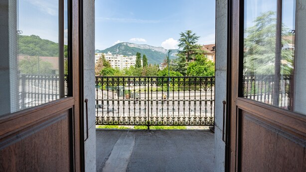 A balcony with a wrought iron railing, a view of a mountain, and buildings in the background. - Le Paradis - Beautiful T3 with nice view on the Visitation (Annecy)