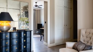 A living room with a dark blue dresser, a beige armchair, a round woven rug, and a large mirror on the wall. - LA MAVÉRIA – Elegant 100 m² flat near Lake Annecy (Annecy-le-Vieux)