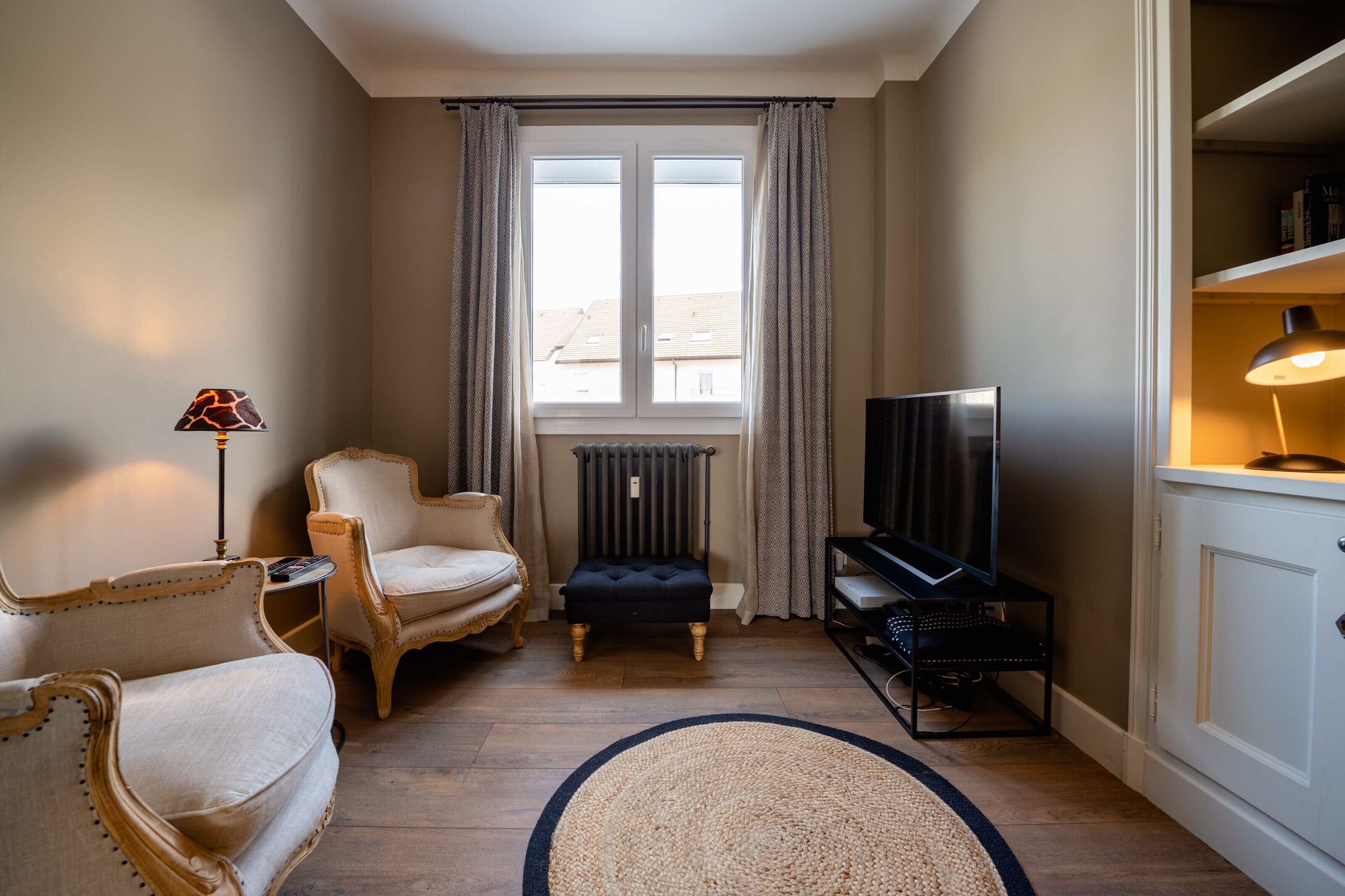 Un salon confortable avec un canapé, un fauteuil, un pouf et un meuble pour la télévision.