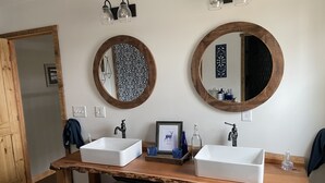 Un bagno con due lavandini, una toeletta in legno e due specchi rotondi.