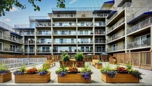 Un edificio residencial de varios pisos con balcones, un patio central con jardineras y un cielo despejado.