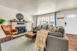 Un salon avec une cheminée, un canapé, une table basse et un fauteuil.