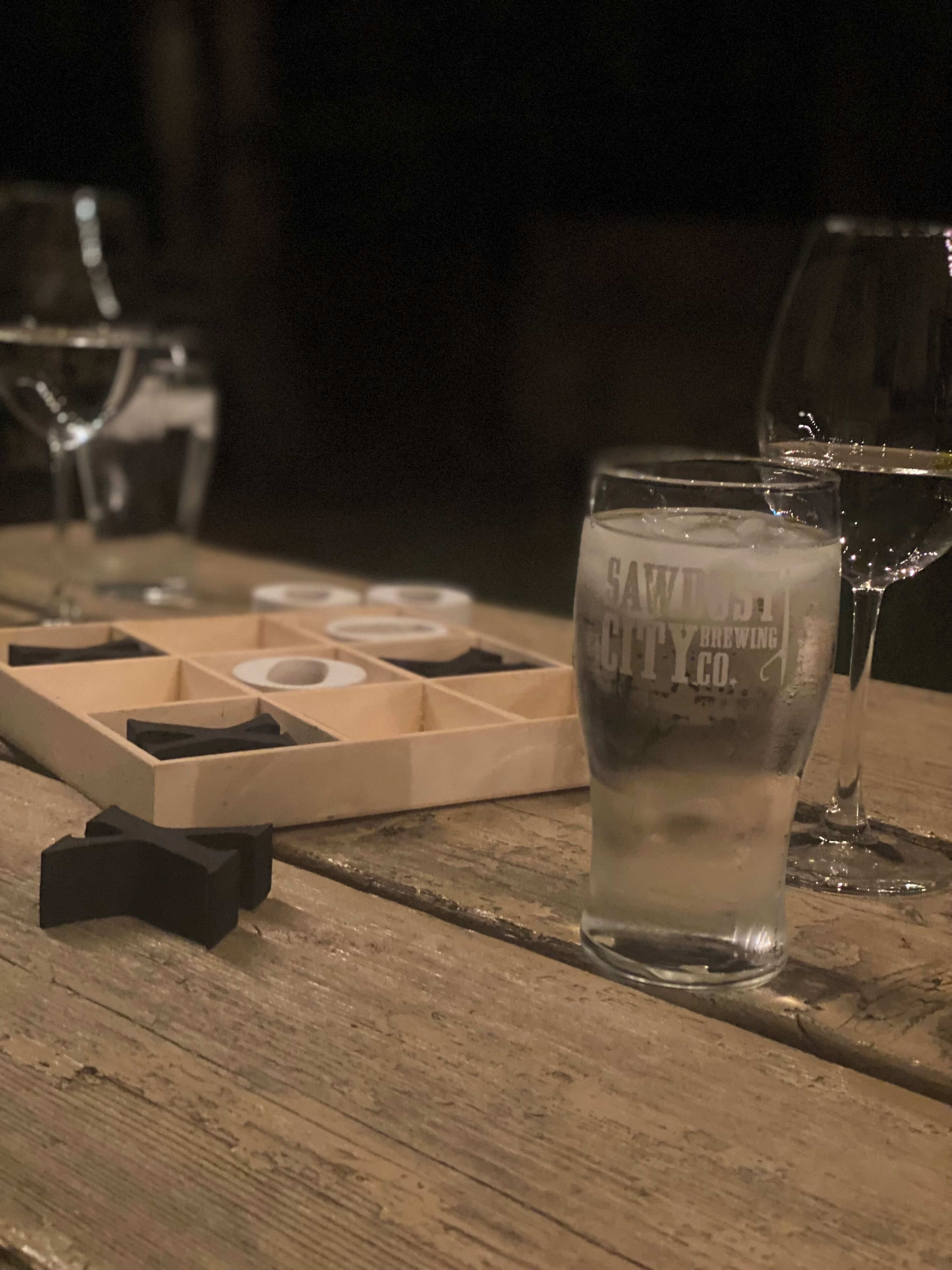 Un tavolo di legno con un bicchiere d'acqua, un sottobicchiere e un vassoio porta sottobicchieri.
