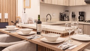 Una cocina luminosa con armarios de madera, una encimera con una botella de vino, vasos y vajilla.