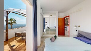 Un dormitorio con cama, vistas al balcón, una silla de madera y una mesita.