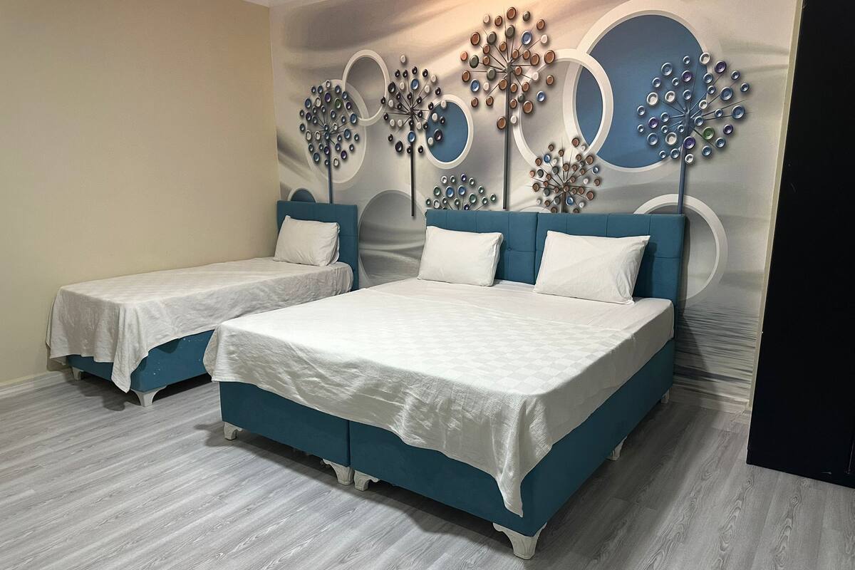 A hotel room with two beds, a modern wall design, and a light wooden floor.