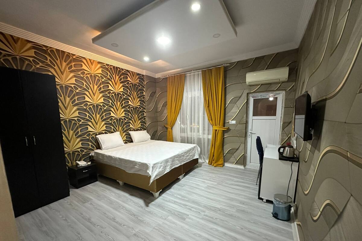 A bedroom with a bed, a wardrobe, a television, and a door.