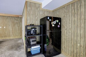 A compact kitchen with a black refrigerator, a metal shelf unit with bags, and a blue cooler. - 51 Mooring Buoy-New Home w/elevator & AMAZING POOL, 2 min walk to the Beach (Hilton Head Island)