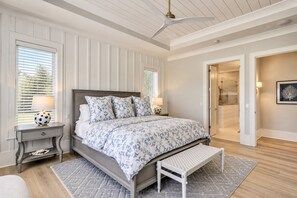 A bedroom with a bed, bedside tables, a bench, and a ceiling fan. - 51 Mooring Buoy-New Home w/elevator & AMAZING POOL, 2 min walk to the Beach (Hilton Head Island)