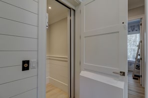 A hallway with a white door, a light switch, and a power outlet on the wall. - 51 Mooring Buoy-New Home w/elevator & AMAZING POOL, 2 min walk to the Beach (Hilton Head Island)