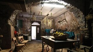 A rustic room with a stone wall, wooden furniture, and a table with a basket of lemons. - La via del sale  (Pignone)