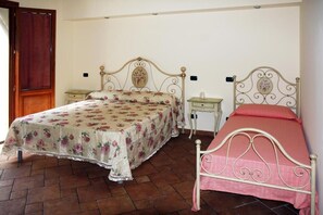 Ein Schlafzimmer mit zwei Betten, einer Holztür und Fliesenboden.