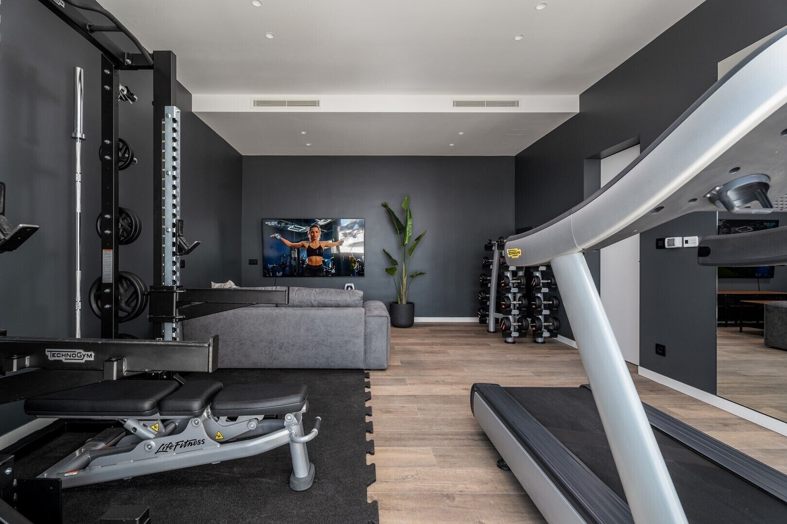 Une salle de sport moderne pour la maison, équipée d’un tapis de course, d’un banc de musculation et de divers appareils d’exercice.