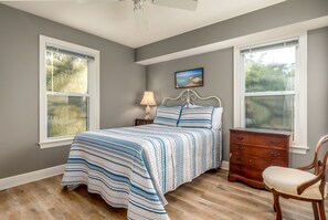 Relax in this serene bedroom with a large bed, nightstand, and dresser.