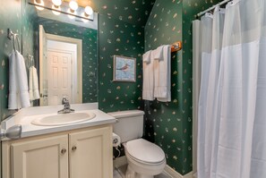 Classic bathroom with a sink, toilet, and shower curtain, adorned with a bird-patterned wallpaper and a framed bird picture.