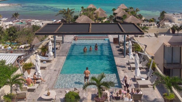 Ein Poolbereich mit Blick auf das Meer, umgeben von Liegestühlen und Sonnenschirmen.