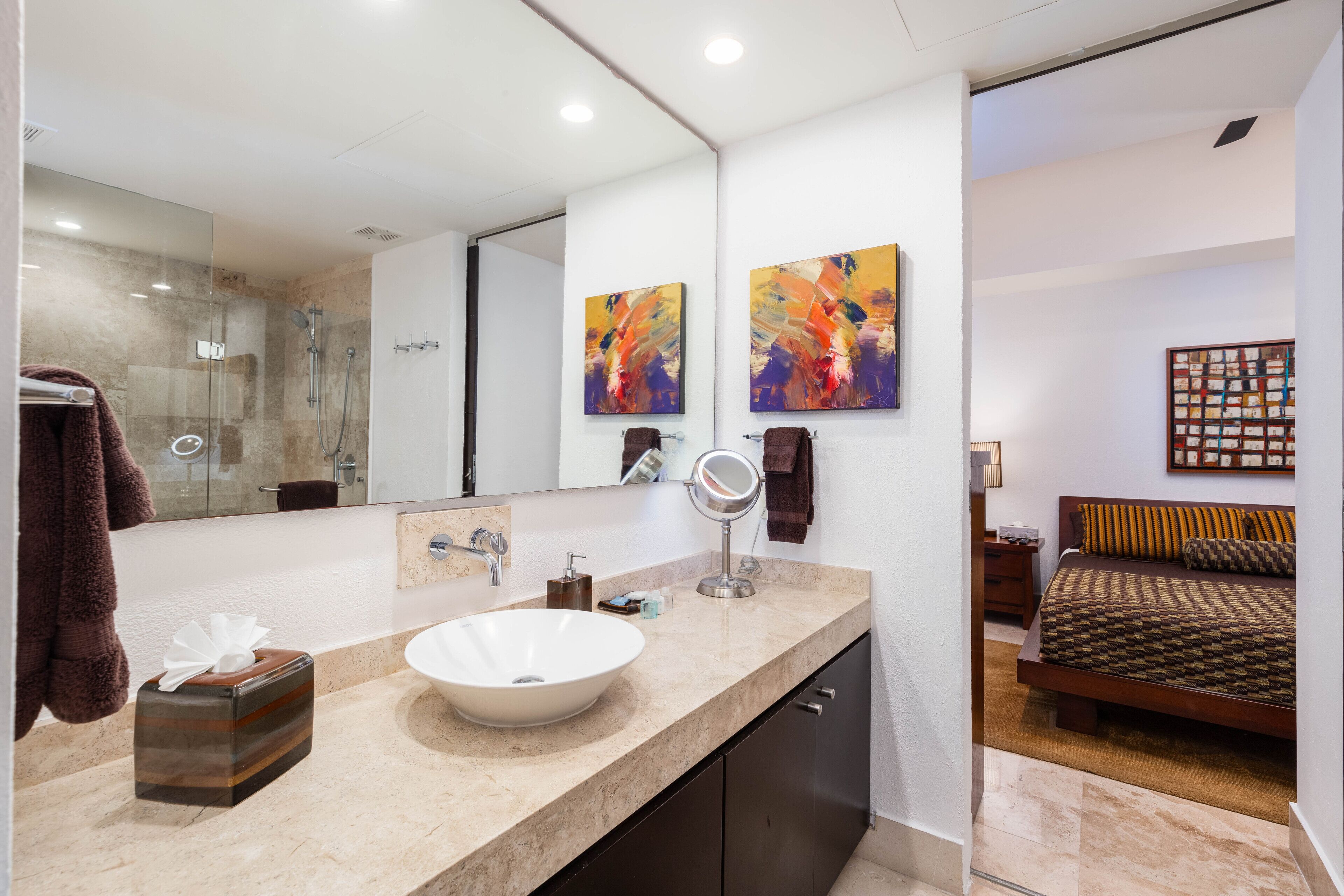 A modern bathroom with a large mirror, a white sink, and a glass shower enclosure.