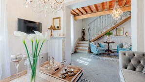 A spacious living room with a high ceiling, a wooden staircase, and a chandelier. - Villa Aperitivo, Romantic and Panoramic Stone Farmhouse with Private Swimming Pool on the Hills of Lucca close to Lucca, Pisa and the Compitese area (Pieve di Compito)