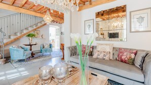 A spacious living room with a high ceiling, wooden beams, a staircase, and a large mirror. - Villa Aperitivo, Romantic and Panoramic Stone Farmhouse with Private Swimming Pool on the Hills of Lucca close to Lucca, Pisa and the Compitese area (Pieve di Compito)