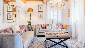 A cozy living room with a grey sofa, a wooden coffee table, and a chandelier. - Villa Aperitivo, Romantic and Panoramic Stone Farmhouse with Private Swimming Pool on the Hills of Lucca close to Lucca, Pisa and the Compitese area (Pieve di Compito)