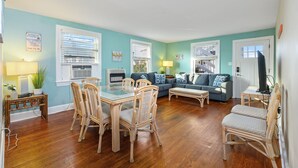 Un salon comprenant un coin repas, avec des meubles en osier, un canapé bleu et un téléviseur.