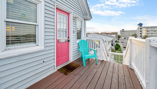 A house with a pink door and a wooden deck.