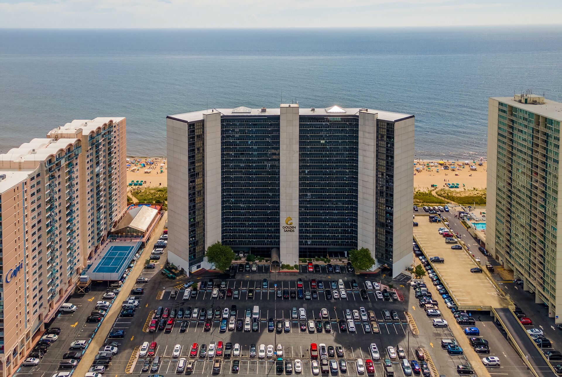 Un hotel moderno de gran altura con estacionamiento frente a una playa y el mar.