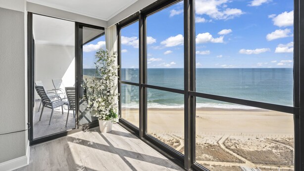 Ein Zimmer mit großen Fenstern mit Blick auf einen Strand und das Meer.