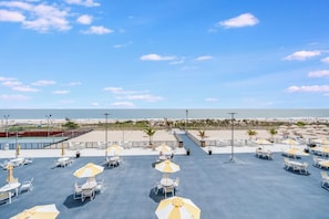 Una terraza en la azotea con mobiliario exterior, vistas a la playa y cielo despejado.
