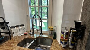 A kitchen with a stainless steel sink, granite countertop, and a window with a view of greenery.