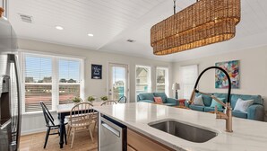 Cocina moderna con una isla grande, armarios blancos y una lámpara colgante de mimbre.