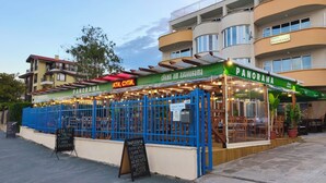 Ein Restaurant namens 'PANORAMA' mit Außenplätzen, einem blauen Zaun und einem Schild in kyrillischer Schrift.
