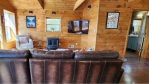 A wooden interior with a leather sofa, a television, and a fireplace. - The Hideaway Spot- Waterfront w/ Dock on Long Cove (Glen Burnie)