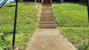A two-story building with a front porch and a flagpole with an American flag. - The Hideaway Spot- Waterfront w/ Dock on Long Cove (Glen Burnie)