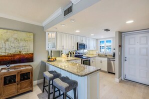 A modern kitchen with white cabinets, a granite countertop, and a large island with bar stools.