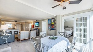 A spacious living area with a dining table, chairs, a ceiling fan, and a kitchen in the background. - NEW Salt Water Pool and Sun Deck Steps to Vanderbilt Beach Water Views (Naples)