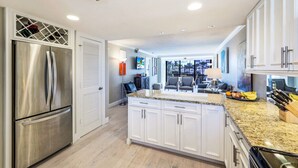 A modern kitchen with white cabinets, stainless steel appliances, and a granite countertop. - NEW Salt Water Pool and Sun Deck Steps to Vanderbilt Beach Water Views (Naples)