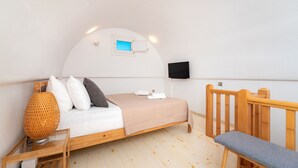 A bedroom with a bed, bedside table, lamp, and a TV mounted on the wall. - Fully equipped house! (Santorini)