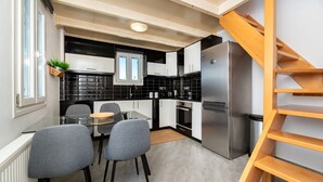 A modern kitchen with a built-in stove, a stainless steel refrigerator, and a wooden staircase. - Fully equipped house! (Santorini)