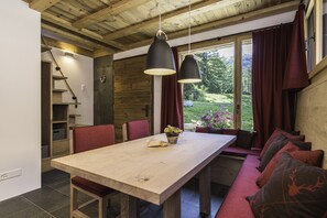 Una mesa de comedor de madera con sillas, un banco con cojines e iluminación colgante.