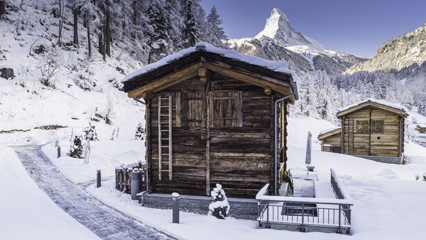 Une cabane en bois avec un escalier en bois et une rambarde en métal à l’avant.
