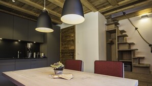 Une cuisine moderne avec des meubles de couleur sombre, un îlot central en bois et des luminaires suspendus.