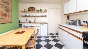 Una cucina funzionale con tavolo in legno, sedie, lavastoviglie e macchina per il caffè.
